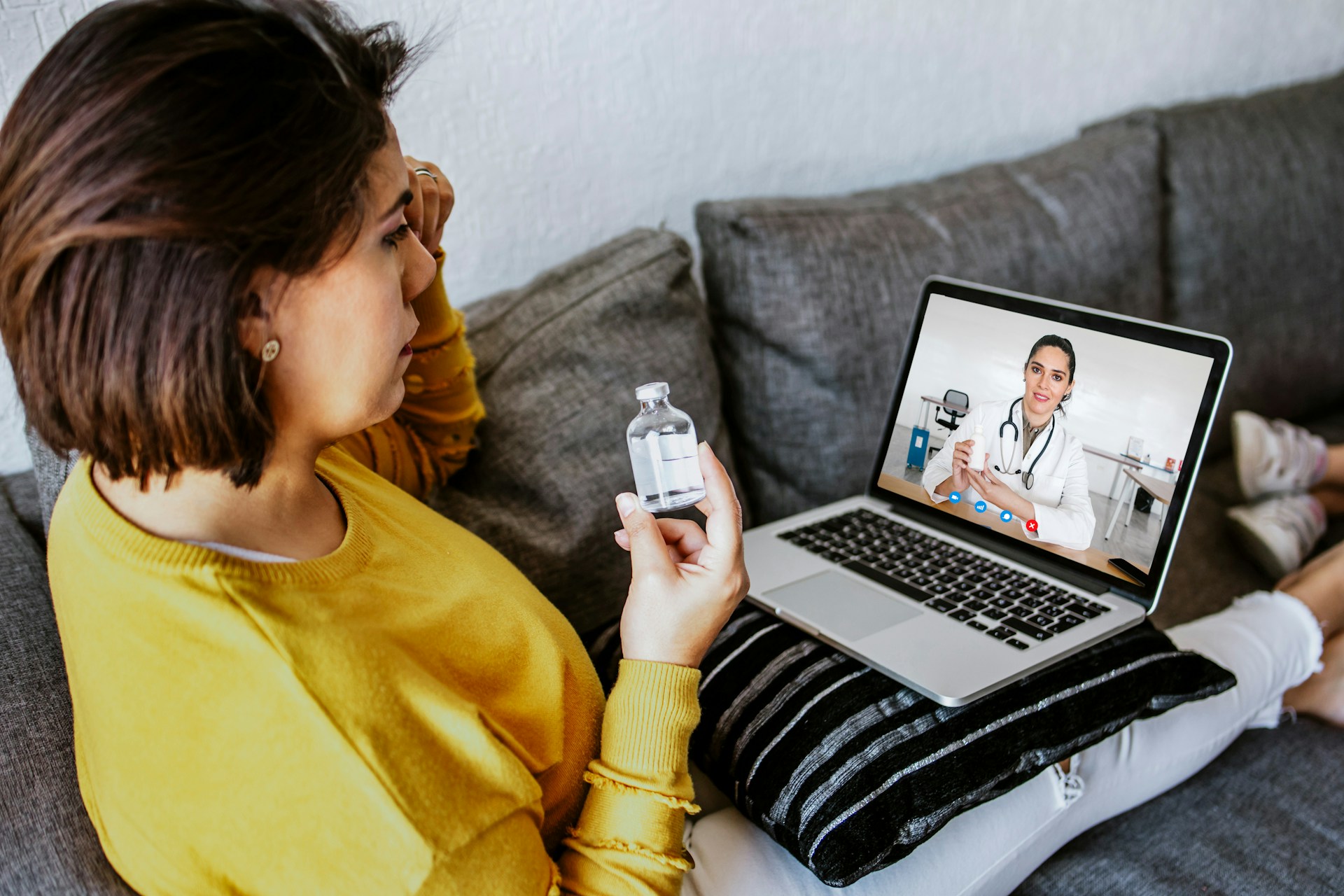 woman sitting with medicine in her hand while watching laptop
